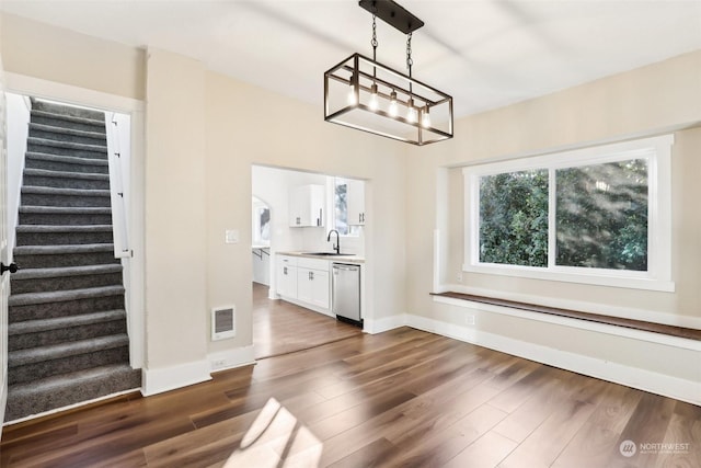 unfurnished dining area featuring sink, a chandelier, and dark hardwood / wood-style floors