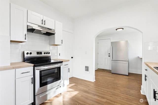 kitchen featuring butcher block countertops, white cabinetry, appliances with stainless steel finishes, light hardwood / wood-style floors, and decorative backsplash