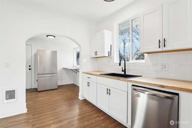 kitchen with butcher block countertops, sink, appliances with stainless steel finishes, white cabinets, and decorative backsplash