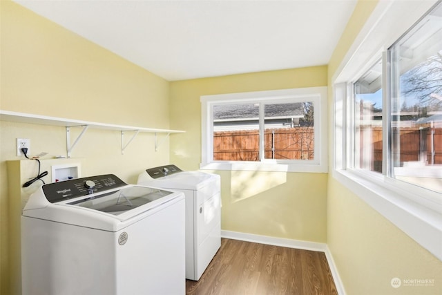 laundry room with a healthy amount of sunlight, hardwood / wood-style floors, and washer and dryer