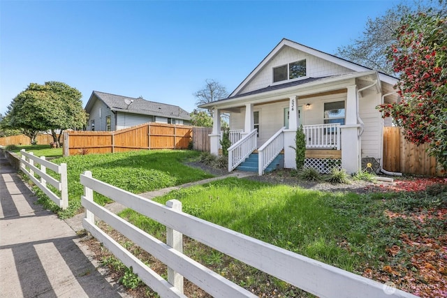 bungalow featuring a front lawn, fence, and covered porch