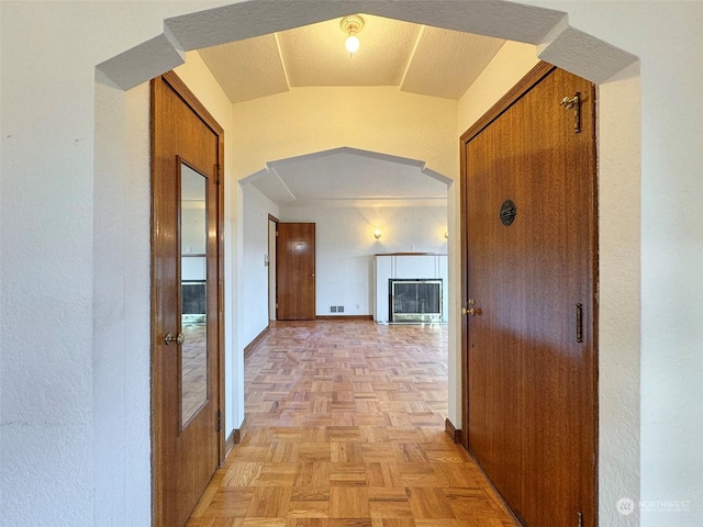 hallway featuring vaulted ceiling and light parquet floors