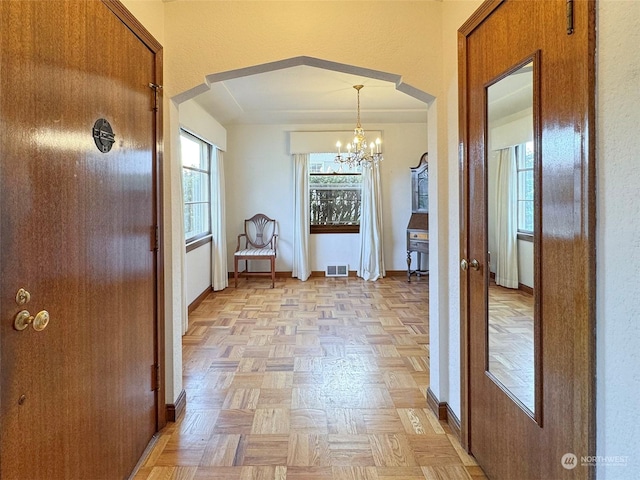 hallway featuring an inviting chandelier and light parquet flooring