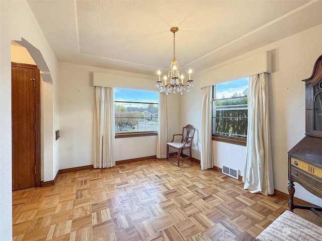 unfurnished dining area with a notable chandelier, plenty of natural light, and light parquet floors