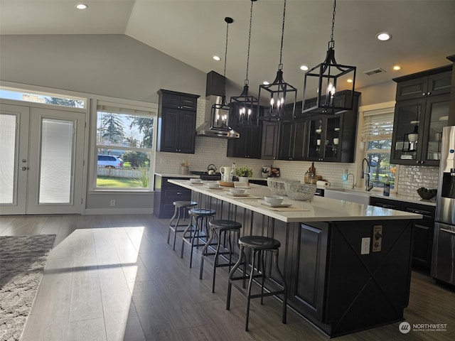 kitchen with dark hardwood / wood-style flooring, wall chimney range hood, and a kitchen island