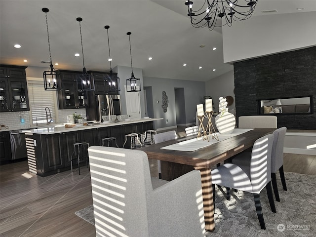 dining space featuring a multi sided fireplace, vaulted ceiling, and sink