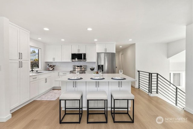 kitchen with appliances with stainless steel finishes, a center island, sink, and white cabinets