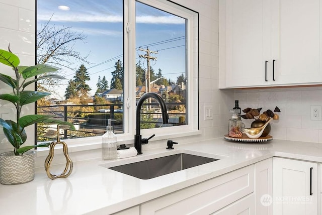 kitchen featuring white cabinetry, sink, a wealth of natural light, and tasteful backsplash