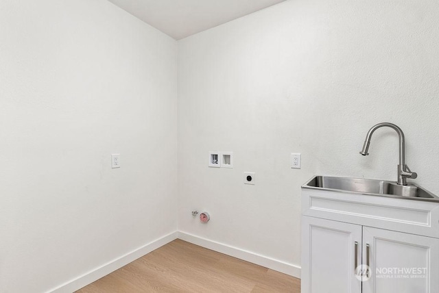 washroom featuring sink, cabinets, washer hookup, hookup for an electric dryer, and light hardwood / wood-style flooring