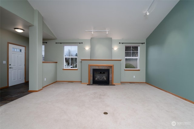 unfurnished living room with lofted ceiling, track lighting, light carpet, and a fireplace