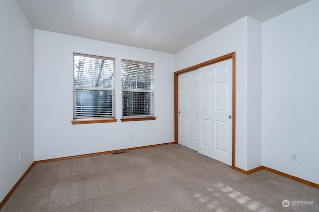 unfurnished bedroom featuring light colored carpet and a closet