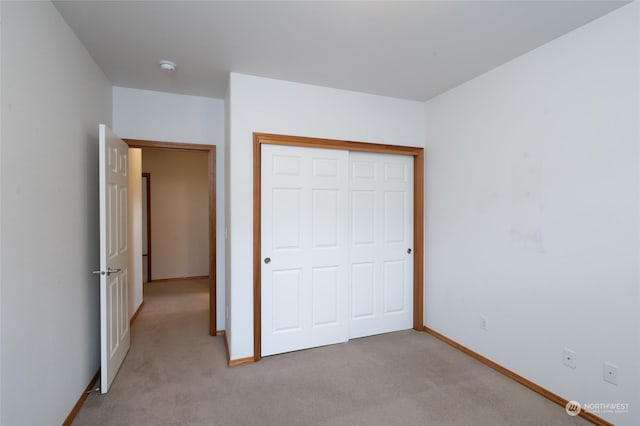 unfurnished bedroom featuring a closet and light carpet