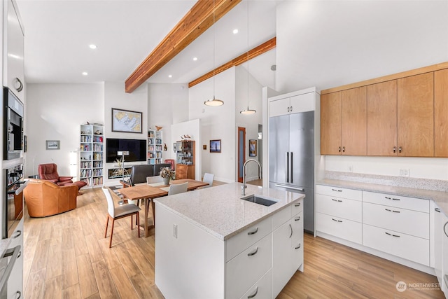 kitchen featuring sink, hanging light fixtures, stainless steel appliances, light stone countertops, and white cabinets