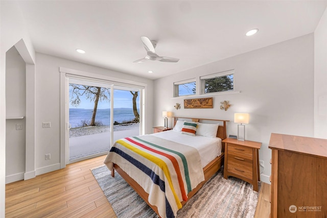 bedroom featuring light hardwood / wood-style flooring, access to outside, ceiling fan, and a water view