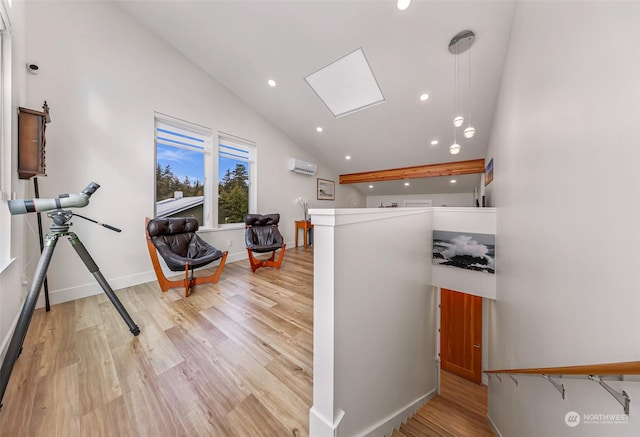 interior space featuring a skylight, a towering ceiling, a wall unit AC, and light hardwood / wood-style flooring