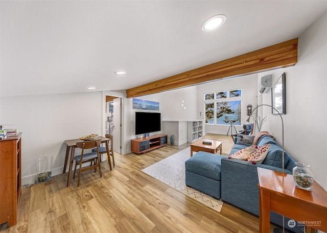 living room featuring beamed ceiling, a wall mounted AC, and light hardwood / wood-style floors