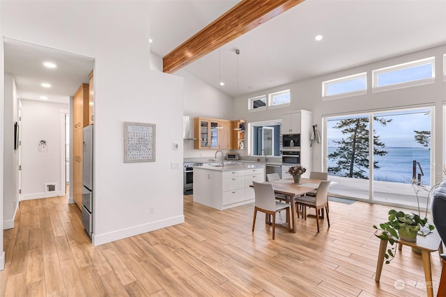 dining space featuring beam ceiling, high vaulted ceiling, sink, and light hardwood / wood-style floors