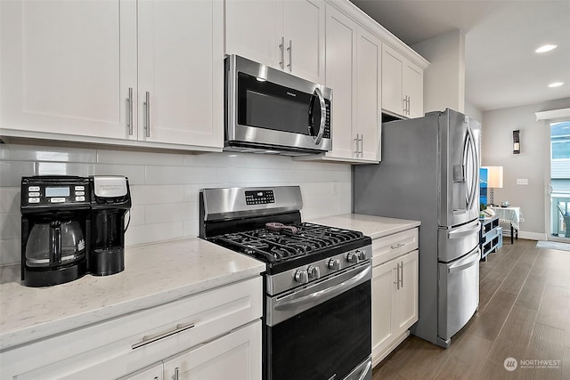 kitchen featuring white cabinetry, stainless steel appliances, light stone countertops, and backsplash