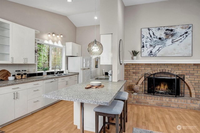 kitchen featuring a breakfast bar, decorative light fixtures, sink, white cabinets, and white appliances