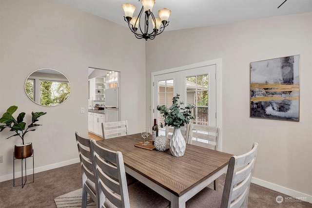 dining space featuring french doors, a notable chandelier, and dark colored carpet