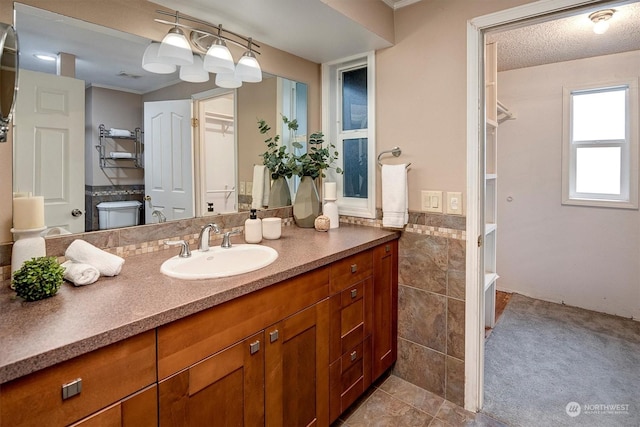 bathroom featuring vanity, toilet, tile walls, and a textured ceiling