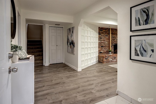 hall featuring brick wall and light wood-type flooring