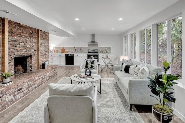 living room with a fireplace, sink, and light hardwood / wood-style flooring