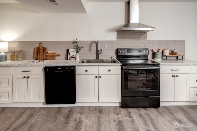 kitchen featuring white cabinetry, wall chimney range hood, black appliances, and sink