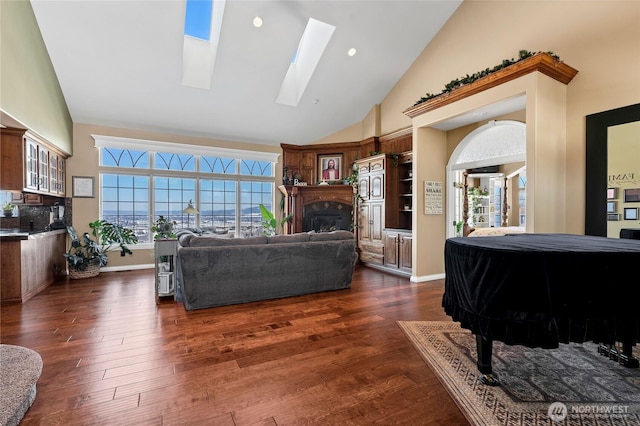 living room featuring a skylight, high vaulted ceiling, and dark hardwood / wood-style floors