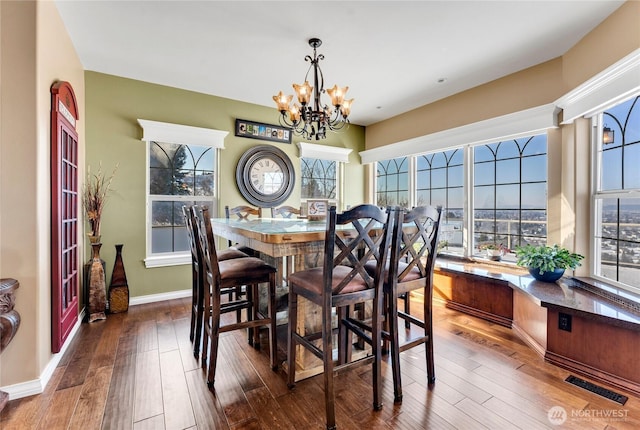 dining space featuring dark wood-type flooring and a notable chandelier