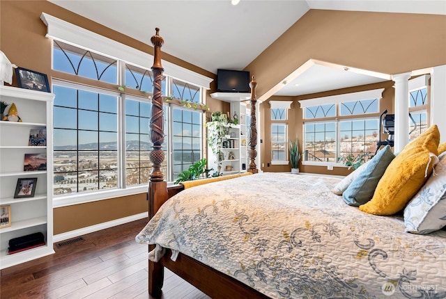 bedroom featuring decorative columns, lofted ceiling, dark wood-type flooring, and multiple windows