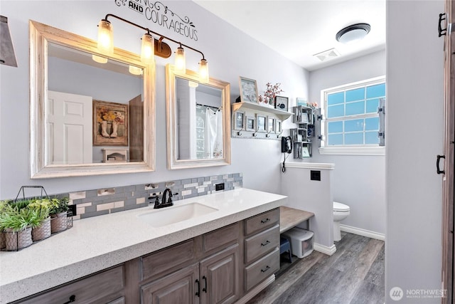 bathroom featuring wood-type flooring, backsplash, vanity, walk in shower, and toilet