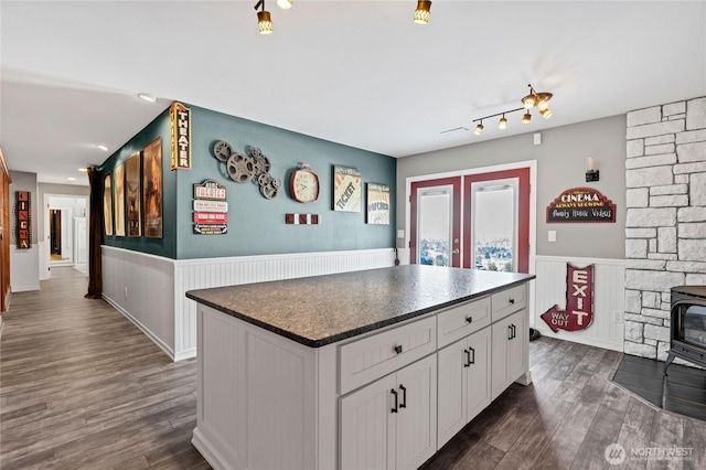 kitchen with a kitchen island, dark hardwood / wood-style floors, a wood stove, white cabinets, and french doors