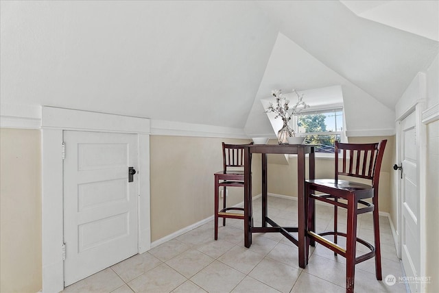 tiled dining area featuring vaulted ceiling