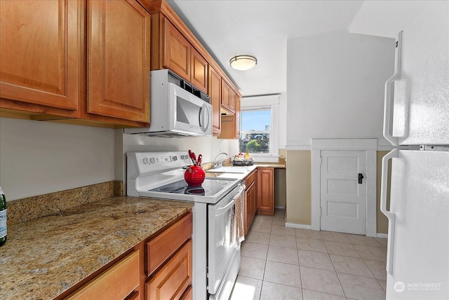 kitchen featuring light stone counters, sink, white appliances, and light tile patterned flooring