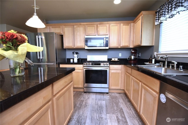 kitchen featuring appliances with stainless steel finishes, light brown cabinetry, sink, dark hardwood / wood-style flooring, and hanging light fixtures