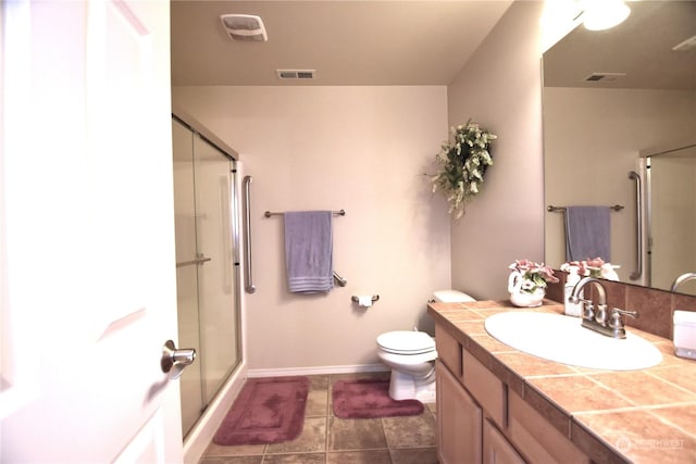 bathroom with tile patterned floors, vanity, toilet, and a shower with shower door