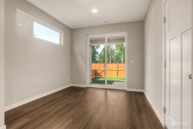 unfurnished room featuring a wealth of natural light and dark hardwood / wood-style floors