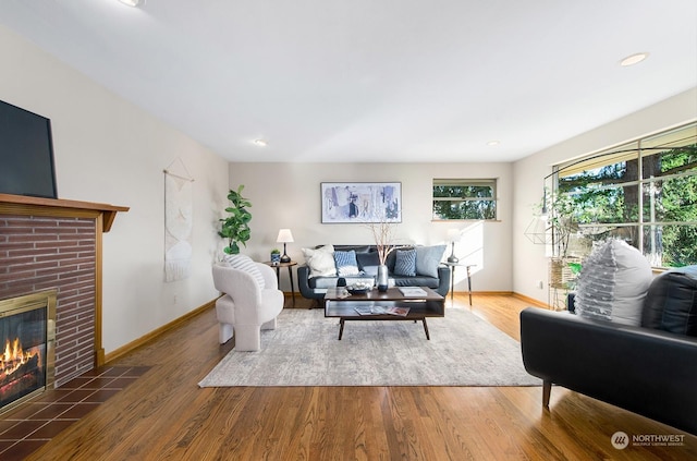 living room with a brick fireplace and hardwood / wood-style floors