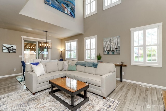 living room with an inviting chandelier, light hardwood / wood-style flooring, and a high ceiling