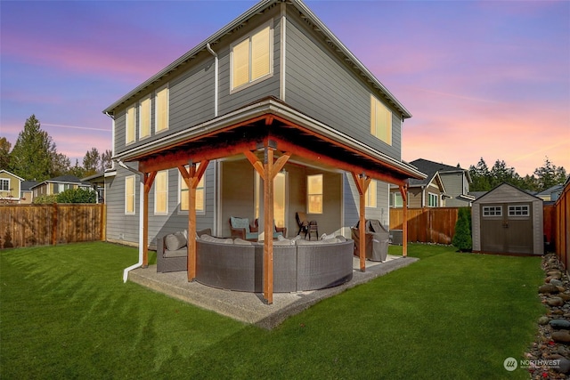 back house at dusk with an outdoor living space, a yard, a storage unit, and a patio