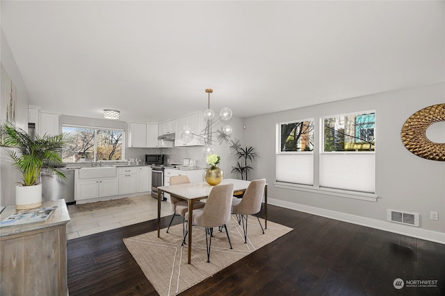 dining space featuring dark hardwood / wood-style floors, a wealth of natural light, and an inviting chandelier