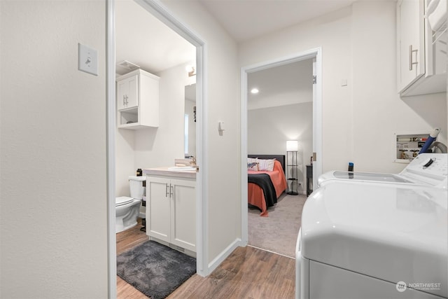 laundry area with sink, cabinets, light hardwood / wood-style flooring, and washer and clothes dryer