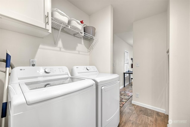 clothes washing area with hardwood / wood-style flooring, washer and clothes dryer, and cabinets