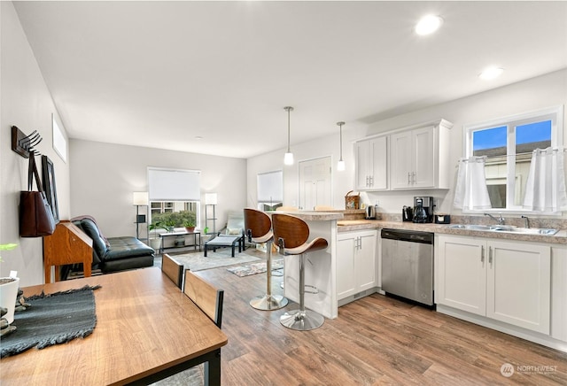 kitchen with sink, stainless steel dishwasher, white cabinetry, and hanging light fixtures