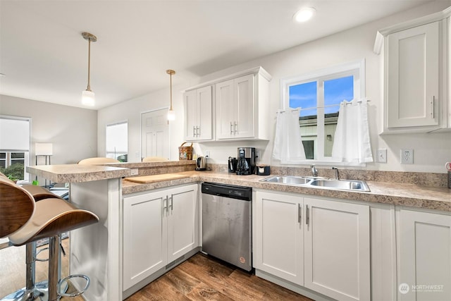 kitchen featuring hanging light fixtures, stainless steel dishwasher, sink, white cabinets, and kitchen peninsula