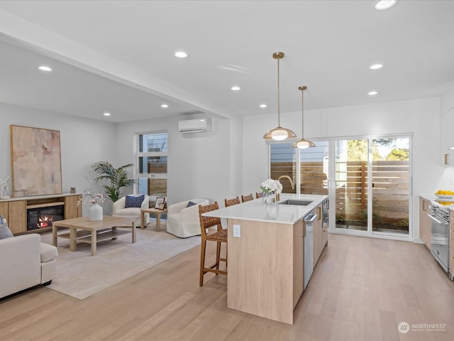 kitchen featuring light hardwood / wood-style floors, sink, hanging light fixtures, light brown cabinetry, and a kitchen island with sink