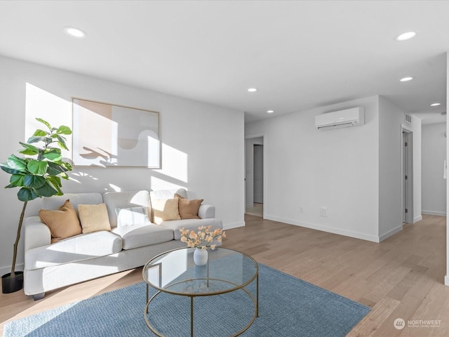 living room featuring an AC wall unit and light hardwood / wood-style floors