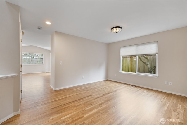 empty room featuring light wood-type flooring and vaulted ceiling