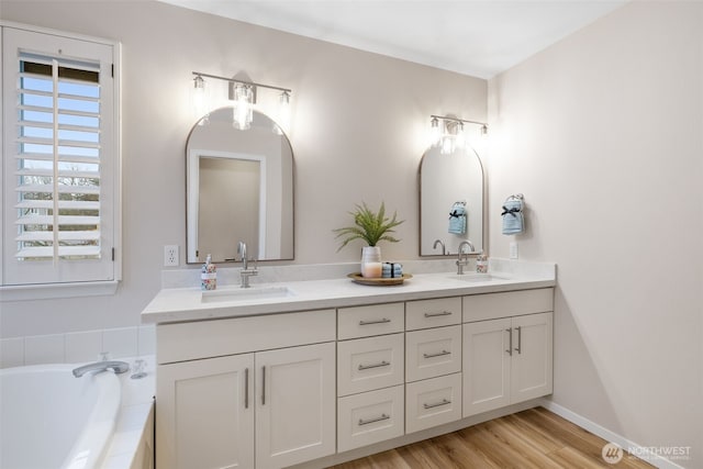 bathroom featuring tiled bath, vanity, and hardwood / wood-style floors